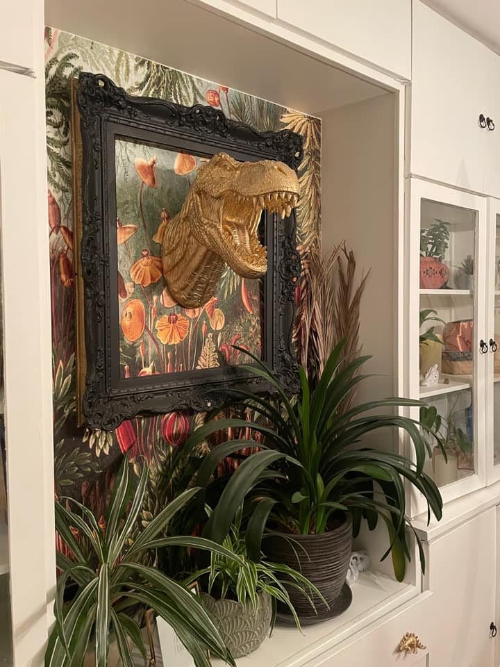 Alcove styled with plants and an ornate framed dinosaur artwork