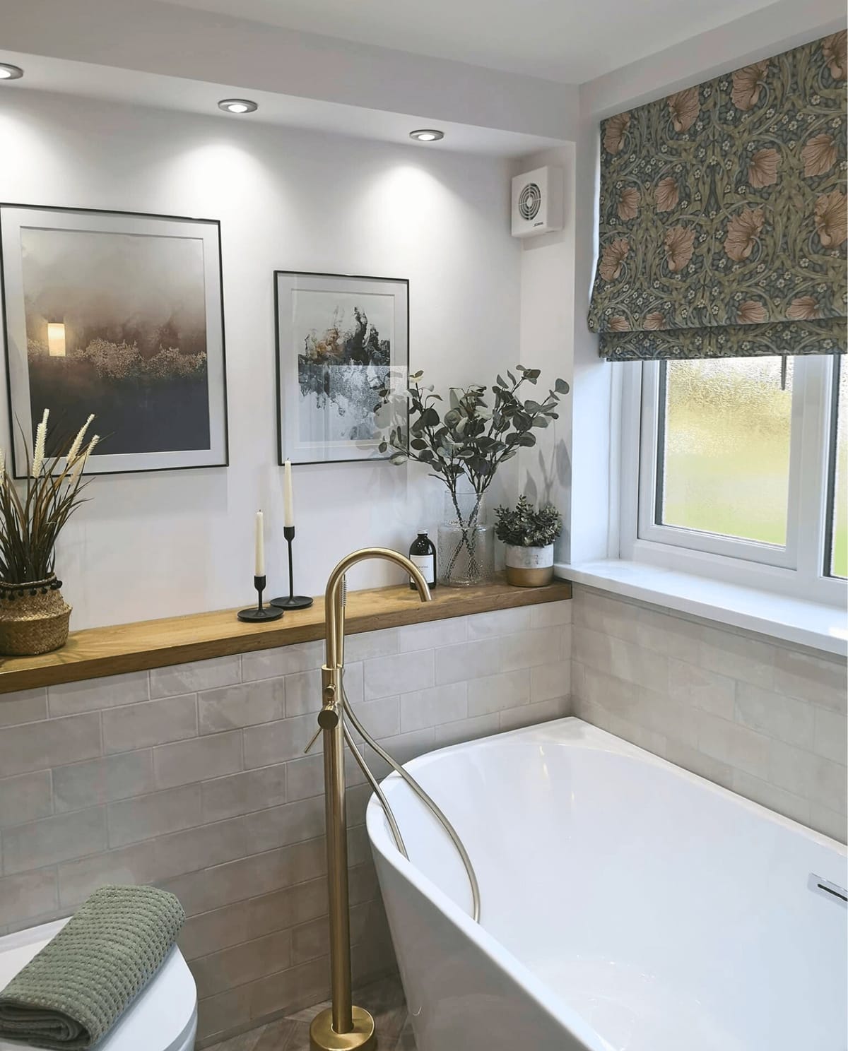 Bathroom with a freestanding bath, brass taps and a patterned blind