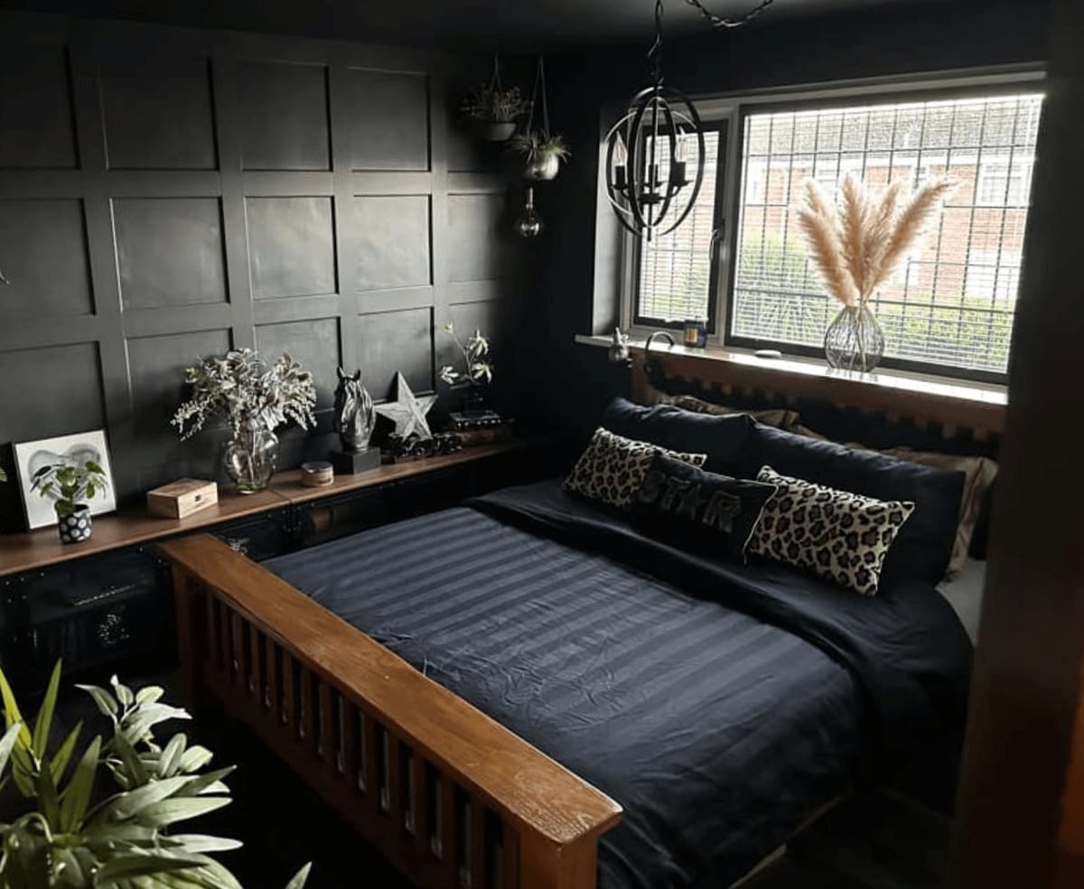 Bedroom with dark wall panelling, a wooden bed frame and plants