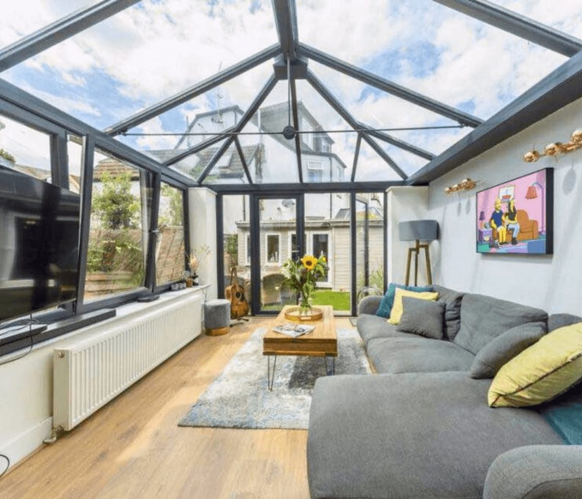 Conservatory lounge with a grey corner sofa and garden views
