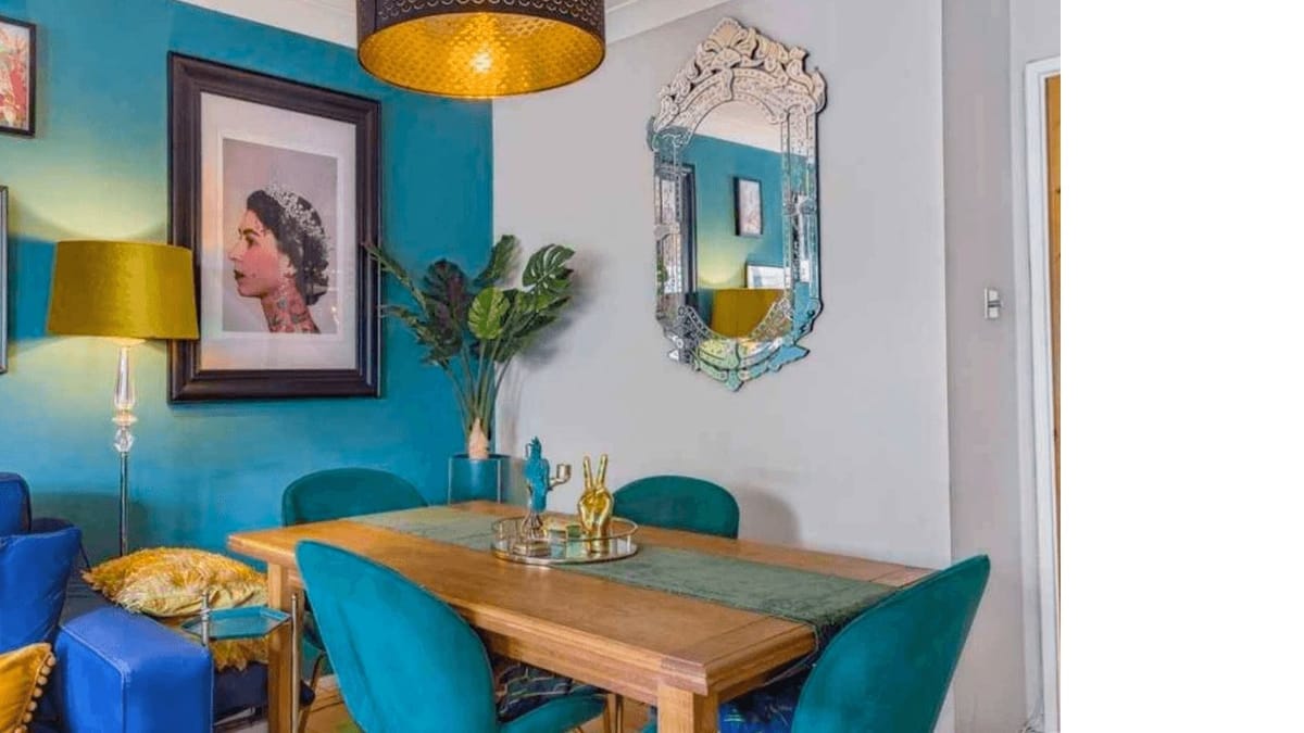 Teal dining room with velvet chairs and a mustard pendant light