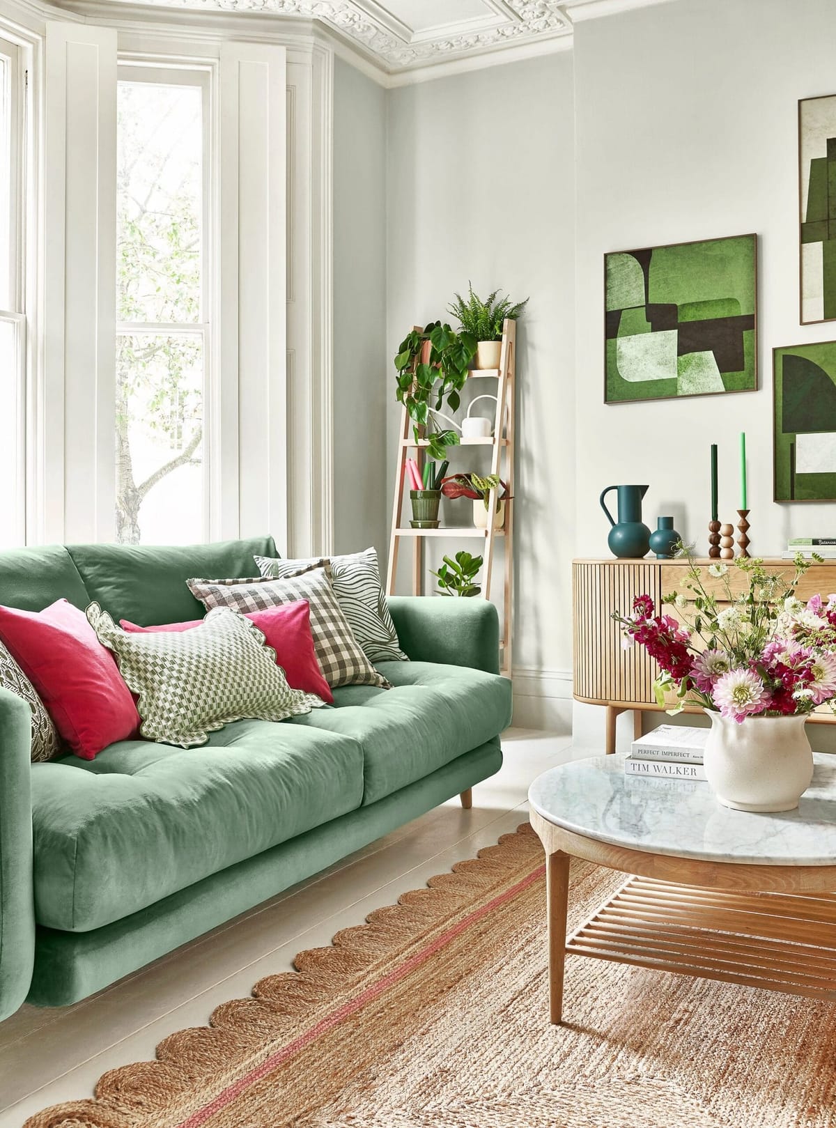 Living room with a green velvet sofa and pink cushions