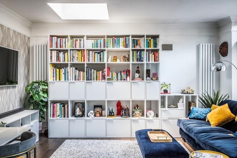 Living room with floor-to-ceiling white bookshelves and a TV wall