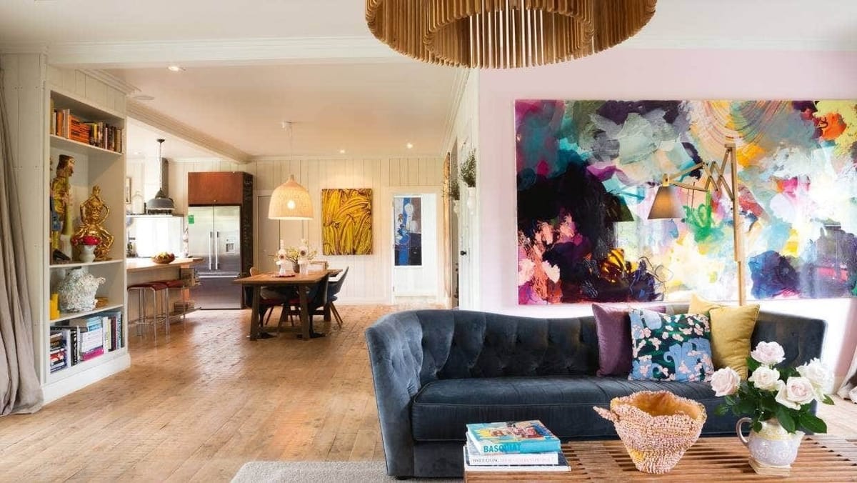 Open-plan living room with a dark sofa and a large colourful painting