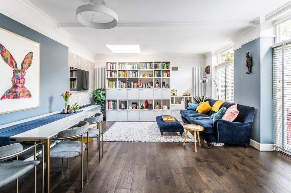 Living room with a large hare artwork, white shelving and a navy sofa