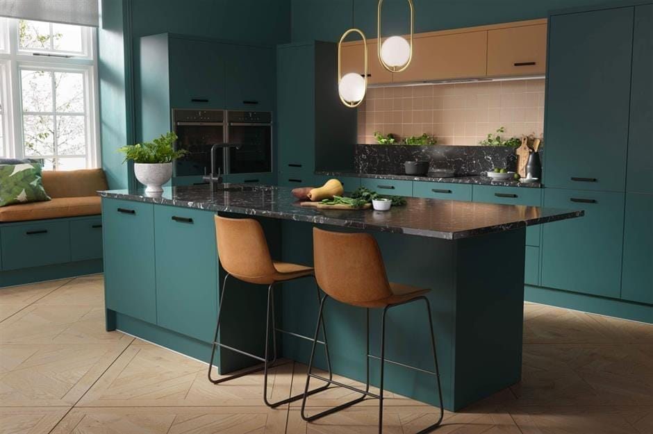 Deep green kitchen with a dark worktop island and tan bar stools