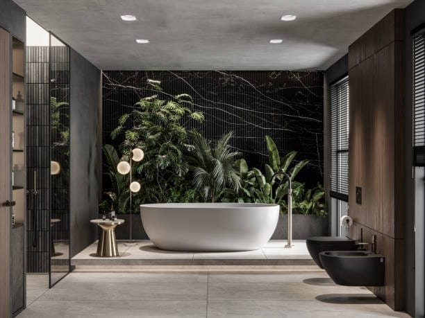 Freestanding bath in a dark marble bathroom filled with plants